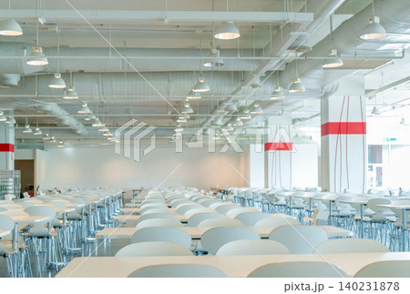 Empty white chair and table in cafeteria of shopping mall. Air duct, air conditioner pipe, and fire sprinkler system. Ventilation system. Building interior. Ceiling lamp light. Interior architecture Empty white chair and table in cafeteria of shopping mall. Air duct, air conditioner pipe, and fire sprinkler system. Ventilation system. Building interior. Ceiling lamp light. Interior architecture 140231878
