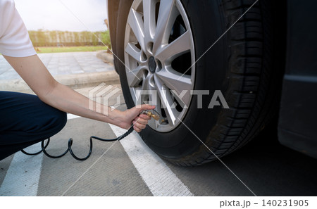 Woman inflates the tire. Woman checking tire pressure and pumping air into the tire of car wheel. Car maintenance service for safety before travel. Tire inflating point. Filling air in the tyre of car 140231905