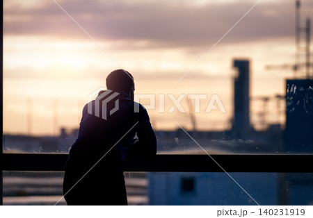 Back view of a man standing and looking through glass window of the airport building to outside. Thinking man. Rear view of a man wear protective face mask waiting for the flight. Travel alone. Back view of a man standing and looking through glass window of the airport building to outside. Thinking man. Rear view of a man wear protective face mask waiting for the flight. Travel alone. 140231919