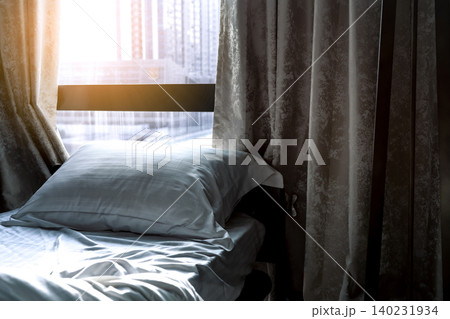 White comfort bed and soft pillow in modern bedroom. Bed near window and curtain at hotel in the morning with sunlight. Linen bed sheet and pillowcase. Bedroom interior design. Sleep with comfortable. White comfort bed and soft pillow in modern bedroom. Bed near window and curtain at hotel in the morning with sunlight. Linen bed sheet and pillowcase. Bedroom interior design. Sleep with comfortable. 140231934
