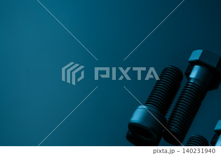 Metal bolts on blue background. Hardware tools. Closeup hex head bolt and socket cap bolt with copy space. Threaded fastener use in automotive engineering. Hexagonal bolt. High strength fasten bolt. Metal bolts on blue background. Hardware tools. Closeup hex head bolt and socket cap bolt with copy space. Threaded fastener use in automotive engineering. Hexagonal bolt. High strength fasten bolt. 140231940