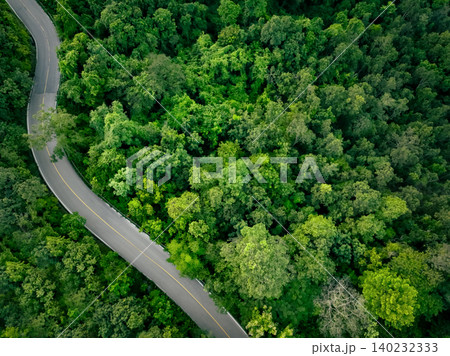 Aerial view of dense green trees in forest capture CO2 and curve highway road. Green trees background for carbon neutrality and net zero emissions concept. Sustainable green environment. Carbon credit Aerial view of dense green trees in forest capture CO2 and curve highway road. Green trees background for carbon neutrality and net zero emissions concept. Sustainable green environment. Carbon credit 140232333