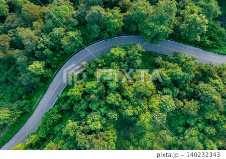 Aerial view of dense green trees in forest capture CO2 and curve highway road. Green trees background for carbon neutrality and net zero emissions concept. Sustainable green environment. Carbon credit Aerial view of dense green trees in forest capture CO2 and curve highway road. Green trees background for carbon neutrality and net zero emissions concept. Sustainable green environment. Carbon credit 140232343