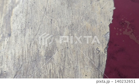 Top view captures rough weathered concrete floor texture borders peeking red painted surface. Distressed cracked cement details form a rustic abstract industrial background backdrop template. 140232651