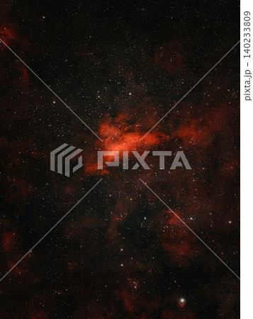 A bright red nebula is visible against a dark sky filled with numerous white stars. A bright red nebula is visible against a dark sky filled with numerous white stars. 140233809