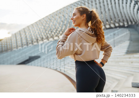 Active woman in sportswear does stretching exercise, looks at fitness application through Smartwatch Active woman in sportswear does stretching exercise, looks at fitness application through Smartwatch 140234333