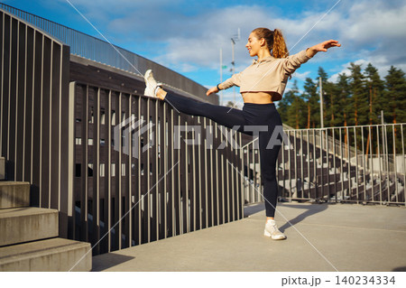 Active woman in sportswear does stretching exercise, looks at fitness application through Smartwatch Active woman in sportswear does stretching exercise, looks at fitness application through Smartwatch 140234334