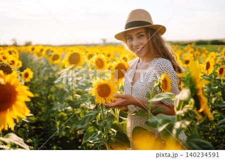 Woman poses in sunflower field in a dress and hat. Enjoy the moment. Active lifestyle. 140234591