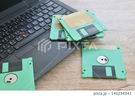 floppy disk old technology for saving data arranging with laptop computer on table 140234841