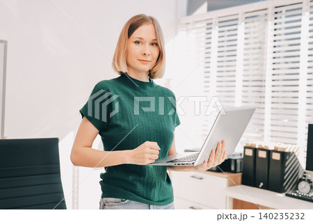 Concept of business working, Businesswoman sitting while writing and checking business analytic document report and holding tablet with computer pc, smartphone on desk in her workstation. Concept of business working, Businesswoman sitting while writing and checking business analytic document report and holding tablet with computer pc, smartphone on desk in her workstation. 140235232