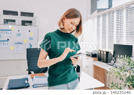 Closeup image of a businesswoman using mobile phone in office Closeup image of a businesswoman using mobile phone in office 140235240