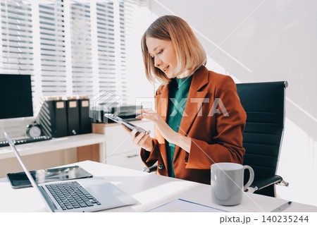 Woman smiling to herself as she works in an office Woman smiling to herself as she works in an office 140235244