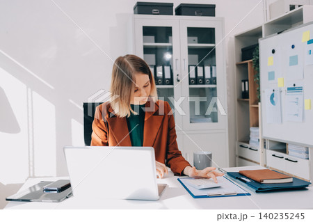 Woman smiling to herself as she works in an office Woman smiling to herself as she works in an office 140235245