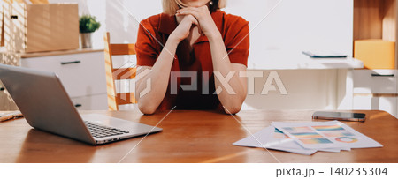 Young woman works on a touchpad, feeling comfortable at cozy home office with a green plant on the background Young woman works on a touchpad, feeling comfortable at cozy home office with a green plant on the background 140235304
