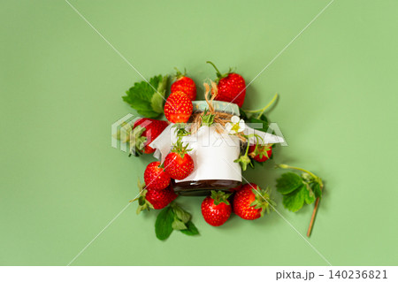 Glass jar of strawberry preserve surrounded by ripe strawberries overhead Glass jar of strawberry preserve surrounded by ripe strawberries overhead 140236821