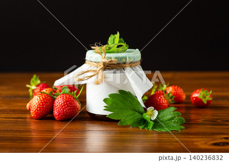 Rustic strawberry preserve surrounded by ripe strawberries 140236832