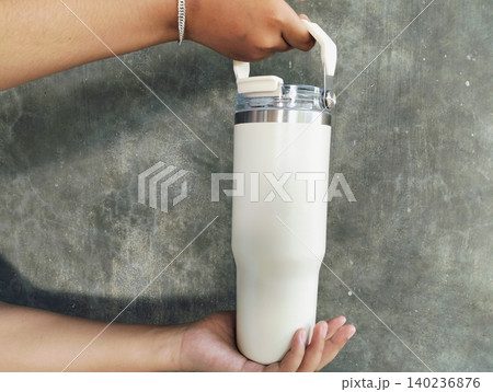 Hand Holding White Tumbler on Concrete Wall Background Hand Holding White Tumbler on Concrete Wall Background 140236876