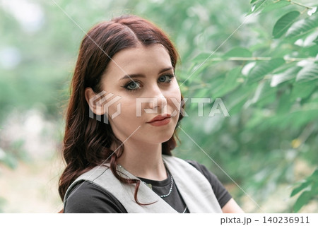 close up of a girl's face against green leaves close up of a girl's face against green leaves 140236911