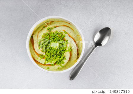 Pistachio ice cream sweet sprinkles and caramel topping in paper cup and spoon on gray background Pistachio ice cream sweet sprinkles and caramel topping in paper cup and spoon on gray background 140237510