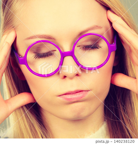 Nerdy woman in big holding head 140238120