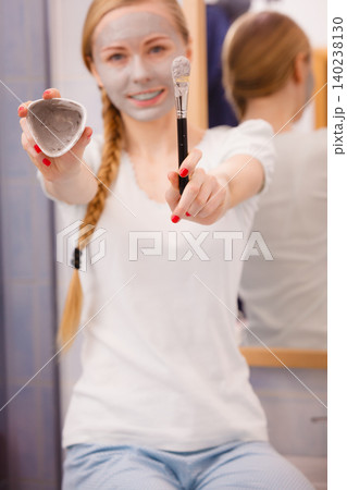 Girl holding clay mud mask and brush. Skin care. 140238130