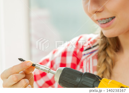 Young woman adjusting her drill Young woman adjusting her drill 140238167