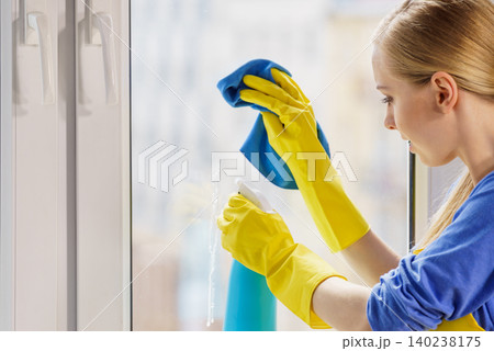 Woman cleaning window at home Woman cleaning window at home 140238175