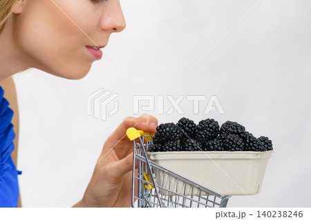 Girl holds blackberry fruits in shopping cart Girl holds blackberry fruits in shopping cart 140238246
