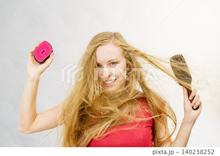 Blonde girl long blowing hair holds two brushes 140238252
