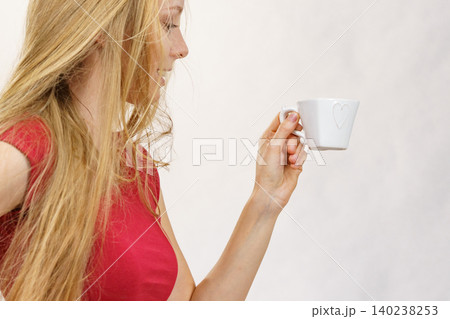 Blonde girl blowing hair holds coffee cup 140238253