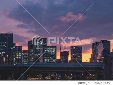 鮮やかな夕焼け空に包まれる都会のスカイラインと高層ビル群のシルエット 鮮やかな夕焼け空に包まれる都会のスカイラインと高層ビル群のシルエット 140239439