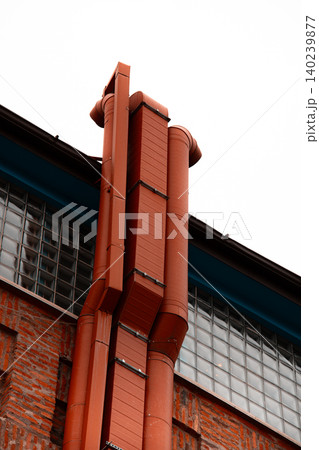 Industrial Ventilation Ducts and Orange Utility Pipes on Brick Wall 140239877