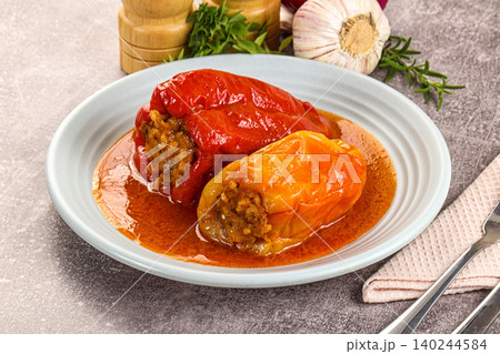 Stuffed red and yellow bell peppers with meat filling in sauce 140244584