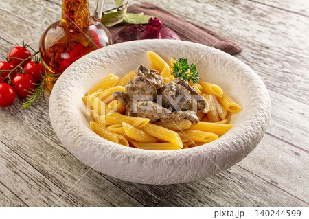 Penne pasta with meat sauce in rustic bowl on wooden table with tomatoes and oil Penne pasta with meat sauce in rustic bowl on wooden table with tomatoes and oil 140244599