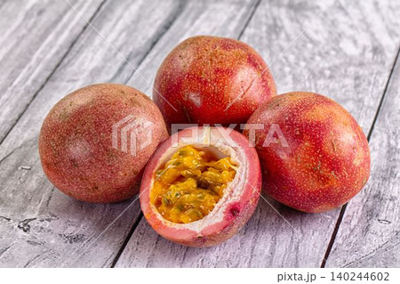 Fresh passion fruit with cut open one revealing juicy seeds on rustic wooden surface Fresh passion fruit with cut open one revealing juicy seeds on rustic wooden surface 140244602