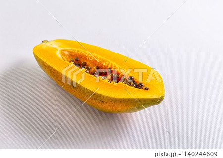 Fresh cut papaya half showing orange flesh and black seeds on white textured background Fresh cut papaya half showing orange flesh and black seeds on white textured background 140244609