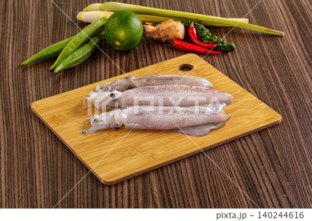 Raw squid on wooden cutting board with fresh herbs and spices Raw squid on wooden cutting board with fresh herbs and spices 140244616