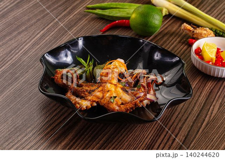 Grilled octopus with herbs and spices on black plate 140244620