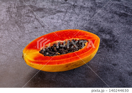 Halved papaya with black seeds on dark stone background Halved papaya with black seeds on dark stone background 140244630