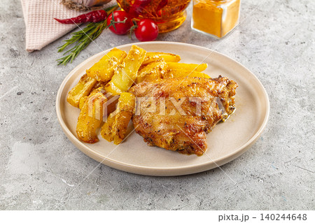 Roasted chicken thigh with seasoned potato wedges on stone background Roasted chicken thigh with seasoned potato wedges on stone background 140244648