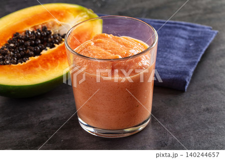 Fresh papaya smoothie in glass with half papaya fruit on dark table Fresh papaya smoothie in glass with half papaya fruit on dark table 140244657