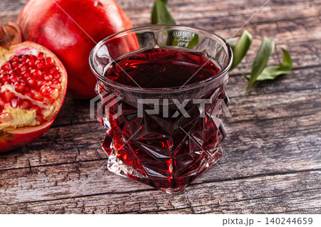 Fresh pomegranate juice in crystal glass with fruit on rustic wooden table Fresh pomegranate juice in crystal glass with fruit on rustic wooden table 140244659