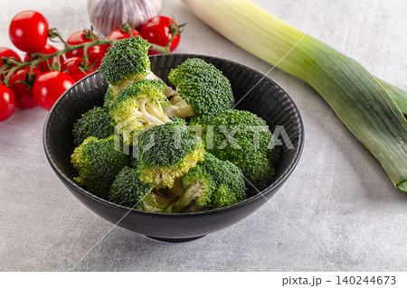 Fresh broccoli florets in bowl with cherry tomatoes, garlic, leek on grey background Fresh broccoli florets in bowl with cherry tomatoes, garlic, leek on grey background 140244673