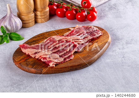Raw sliced beef on wooden cutting board with fresh vegetables and spices Raw sliced beef on wooden cutting board with fresh vegetables and spices 140244680