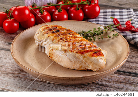 Grilled chicken breast with fresh tomatoes and herbs on wooden table Grilled chicken breast with fresh tomatoes and herbs on wooden table 140244681