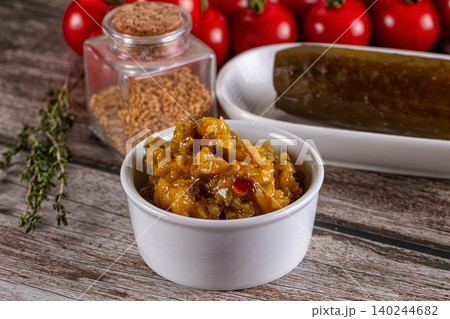Yellow relish in white bowl with pickled cucumber and mustard seeds 140244682