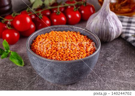 Bowl of red lentils with tomatoes and garlic on stone background 140244702