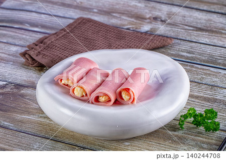Ham and cheese rolls on white plate with parsley on wooden table Ham and cheese rolls on white plate with parsley on wooden table 140244708