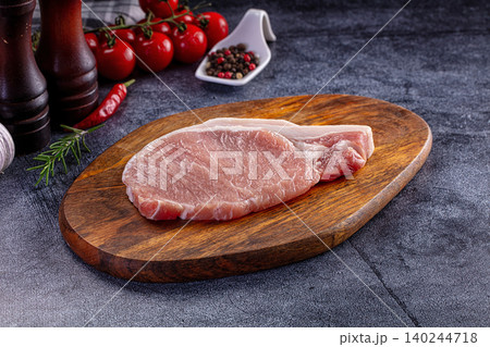 Raw pork steak on wooden board with spices and vegetables Raw pork steak on wooden board with spices and vegetables 140244718