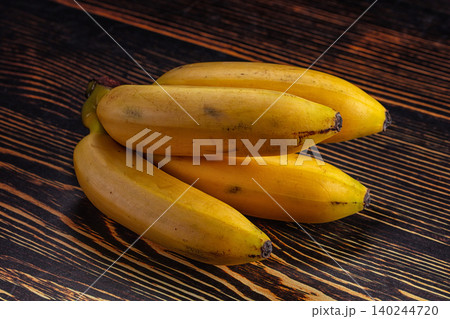 fresh yellow bananas on dark wooden table 140244720